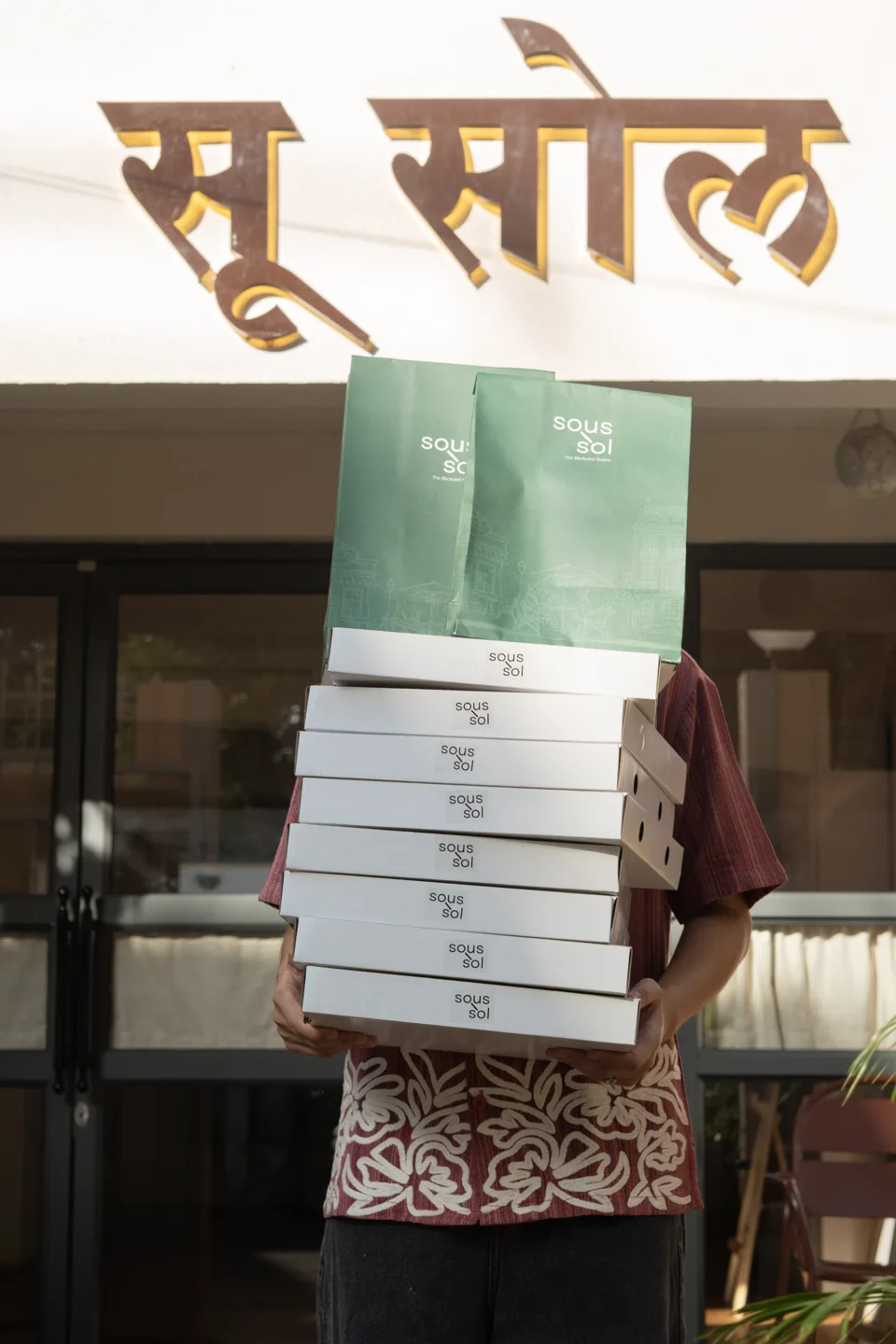 Takeaway coffee cups and a green bag outside Café Soussol