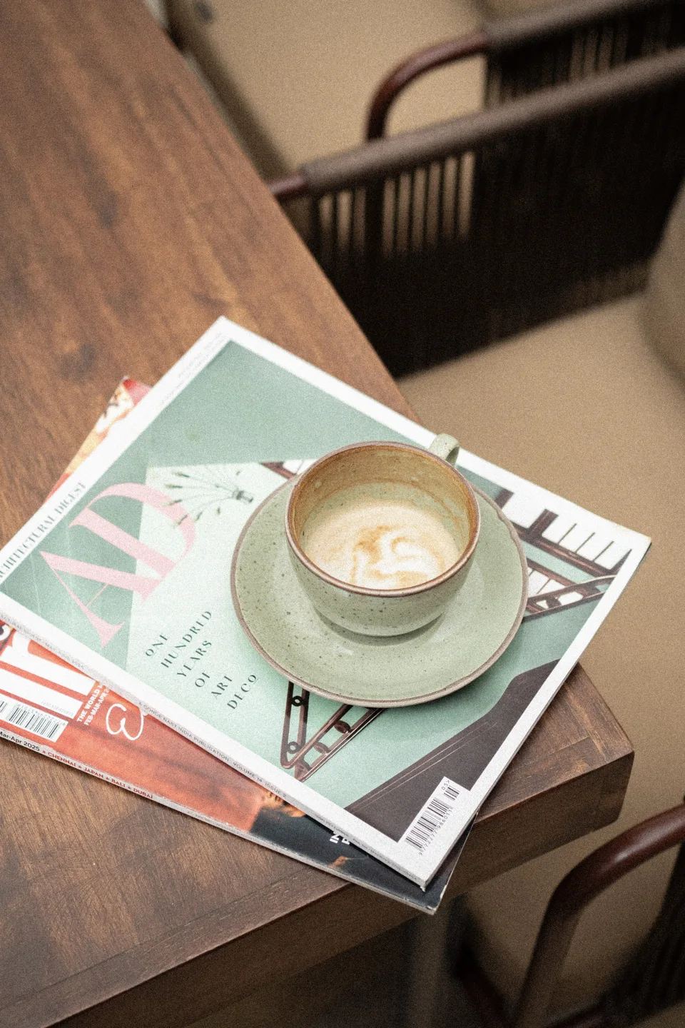 A green cup of coffee on magazines beside a café window