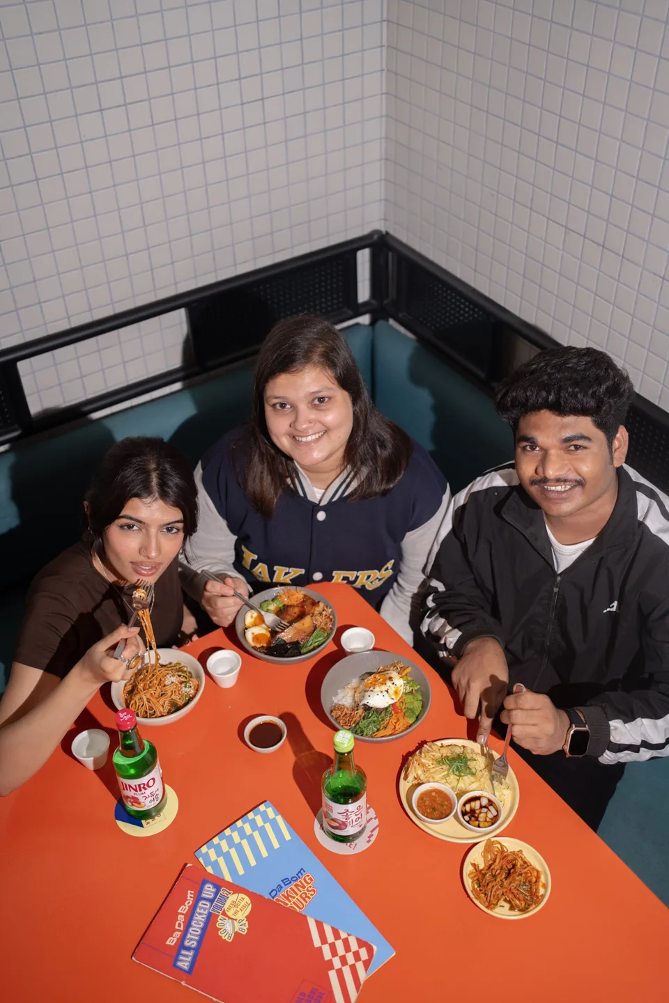 Friends gathered around a bright orange restaurant table