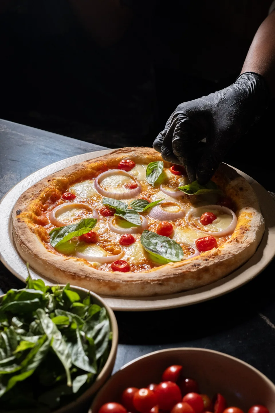 A gloved hand serving freshly baked pizza